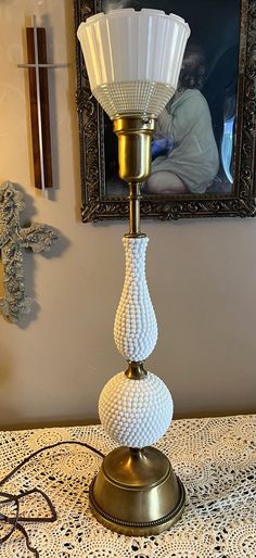 a white lamp sitting on top of a table next to a framed picture above it