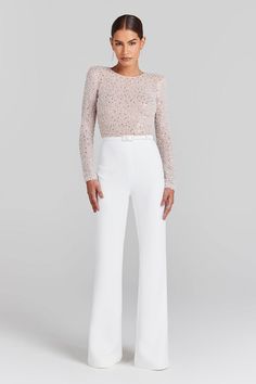 a woman is wearing white pants and a sheer top with sequins on it