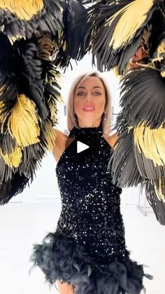 a woman in a black dress is holding two large yellow and black feathered pom poms