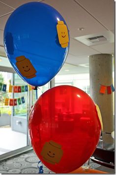 two balloons with faces on them hanging from the ceiling