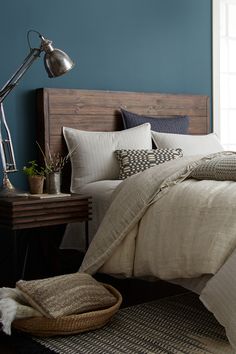 a bed in a bedroom with blue walls and wooden headboard, pillows and blankets