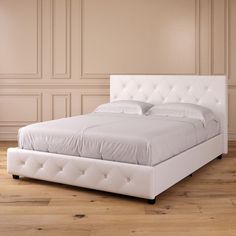 a white bed sitting on top of a wooden floor