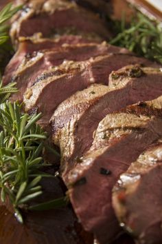 slices of roast beef with rosemary garnish on a cutting board