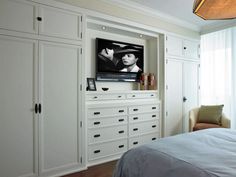 a flat screen tv mounted to the side of a white cabinet