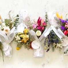 three bunches of flowers tied to each other on a white surface with the words love written on them