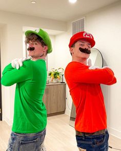 two men with fake moustaches on their faces are standing in front of a mirror