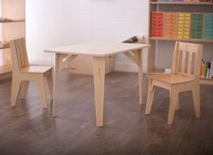 two children's wooden chairs and table in a room with books on the shelves