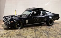 an old race car with the number 69 on it's hood parked in a garage