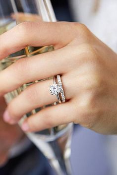 a close up of a person holding a wine glass with a diamond ring on it