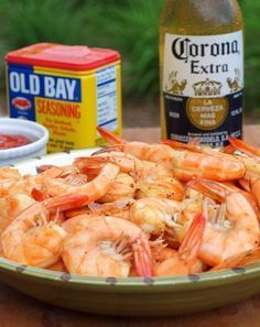 a plate full of shrimp next to a bottle of beer