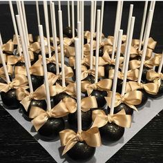 there are many black and gold candies with bows on them in the shape of hearts