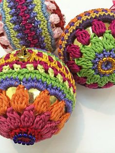 three crocheted ornaments are sitting on a white surface, one is multicolored and the other has an ornament