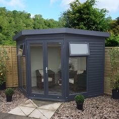 a small garden room in the middle of a yard with gravel and plants around it