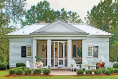 a small white house sitting in the middle of a lush green field