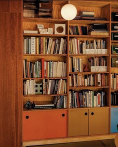 a bookshelf filled with lots of books next to a wall mounted light fixture