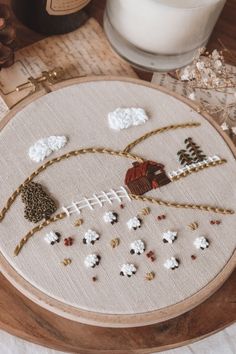 a close up of a embroidery on a table with a candle and some other items