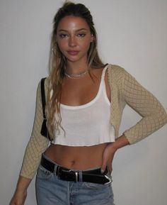 a woman with her hands on her hips wearing jeans and a white top is posing for the camera