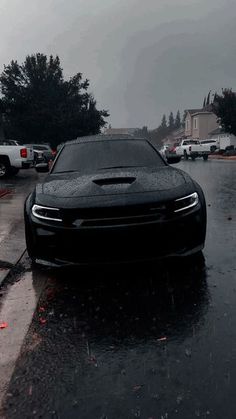 a black car parked on the side of a wet road