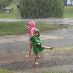 two children in raincoats playing with an umbrella