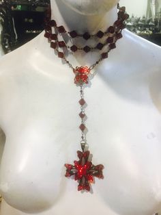 This is a beautiful red long necklace that can be adjusted and used multi ways. Wrap it around your neck for a choker look or adjust it to fit however you wish. Ruby red crystal beads plated in black . Cross has crystals on both sides. Red Gothic Cross Necklace, Spiritual Red Cross Pendant Necklace, Red Adjustable Cross Necklace, Adjustable Red Cross Necklace, Rosary Style Necklace, Silver Mask, Silver Drop Necklace, Black Cross, Star Ruby