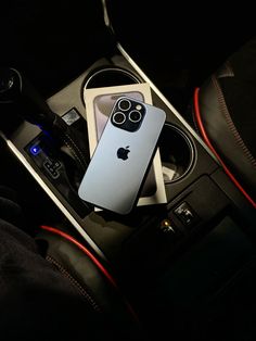 an iphone is sitting in the center console of a car with other accessories around it