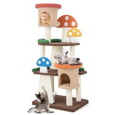 two cats playing in front of a mushroom shaped cat tree with mushrooms on it and one cat laying down