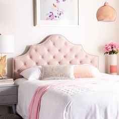 a pink bed with white sheets and pillows on top of it next to a painting