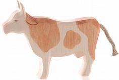 a wooden toy cow standing on top of a white floor