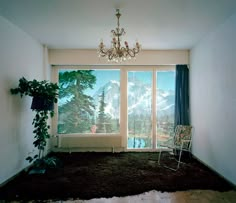 a room with a large window and a chair in front of the window that has a view of mountains