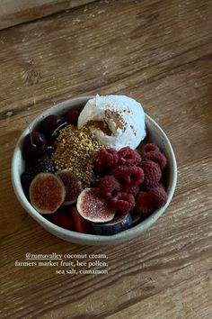 a bowl filled with fruit and ice cream on top of a wooden table next to a cup of coffee