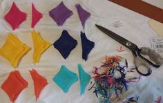 the scissors are laying next to different colored pieces of fabric