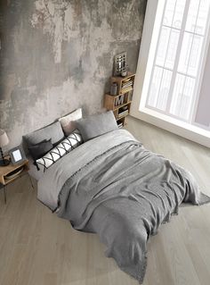 a large bed sitting next to a window in a bedroom on top of a hard wood floor