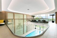 an indoor swimming pool in the middle of a room with glass railing and chandelier