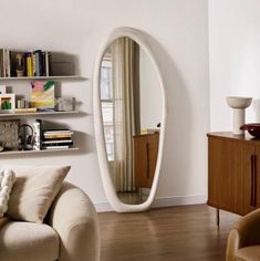 a living room filled with furniture and a large white mirror on the wall above it