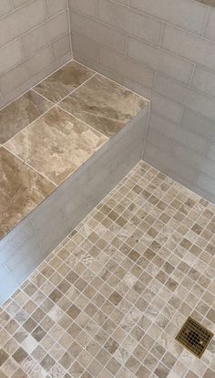 a tiled shower stall with no door and tile flooring on the walls, next to a toilet