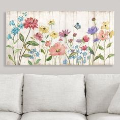 a living room with a white couch and painting on the wall above it that has colorful flowers