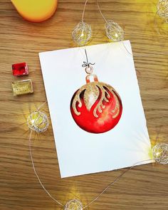 a christmas ornament hanging from a string on top of a piece of paper