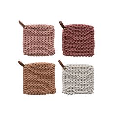 four knitted coasters are shown in three different colors, one is white and the other is pink