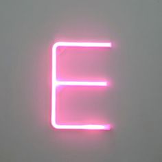 a neon sign that is on the side of a wall in front of a white wall