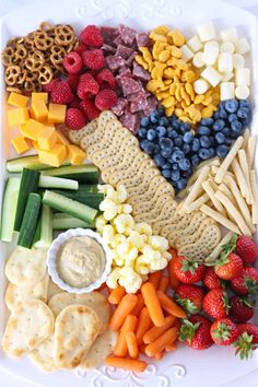 a white plate topped with crackers, fruit and veggies