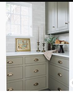 a kitchen with gray cabinets and gold pulls on the countertop, along with candles