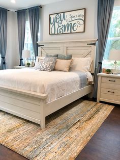 a bedroom with a bed, dressers and rug in front of the window that says new home