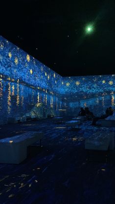 people are sitting on benches in the middle of a room with blue walls and lights