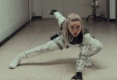 a woman in white and black outfit doing a handstand on the floor with her legs spread out