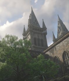 an old building with steeples and trees in the foreground