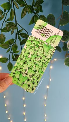 a person holding up a green ticket with barcodes on it and lights in the background