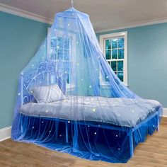 a bed with a blue canopy over it in a room that has hardwood floors and light blue walls