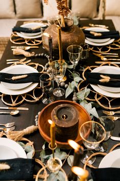 the table is set with black, white and gold place settings for an elegant dinner