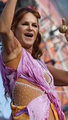 a woman in a belly dance outfit holding her hands up