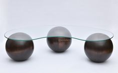 three glass and metal balls sitting on top of a white table next to each other